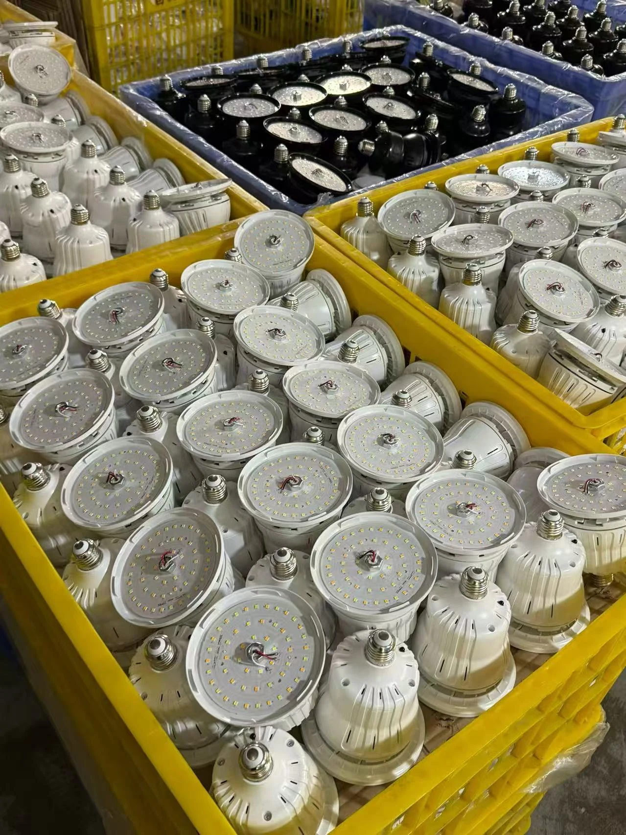 Circular LED boards and white and black E27 housings arranged in factory returnable bins