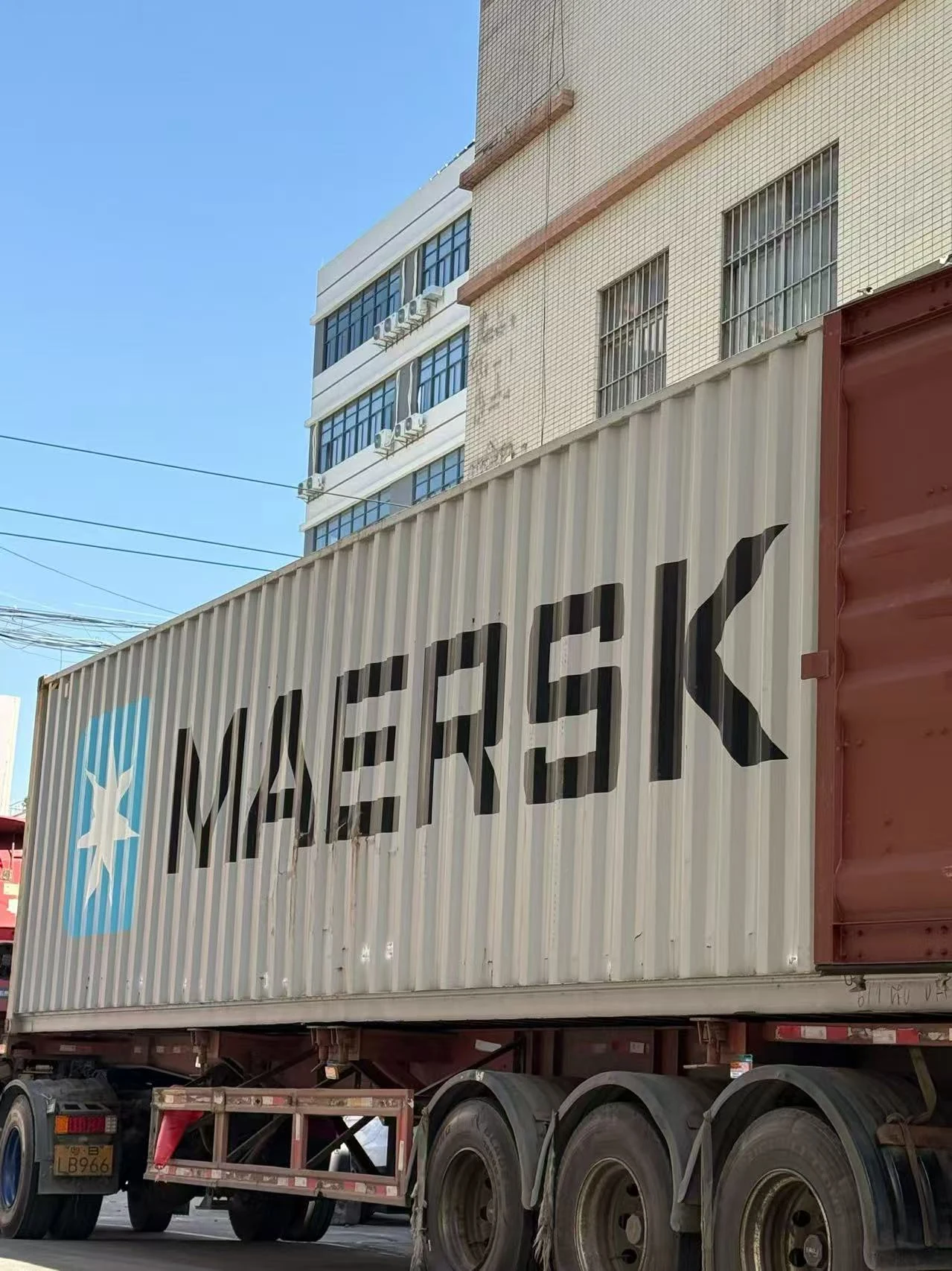 Shipping container on a truck beside industrial buildings